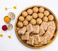 Huldi or turmeric and kumkum or kum kum with tilgul laddu or laddoo in silver bowl, sweet dish in Makar Sankranti festival in hindu religion in India, Indian sweet, isolated on white background
